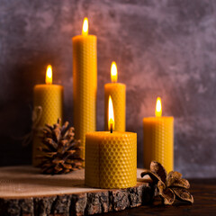 A handmade of natural wax with texture of honeycomb bees candles burns on the table, an unusual...