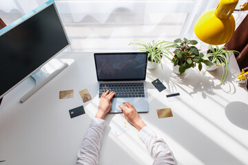 overhead top view hands on laptop keyboard. bank credit cards around