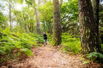 Obraz premium cute young girl running and jumping with her dog in nature
