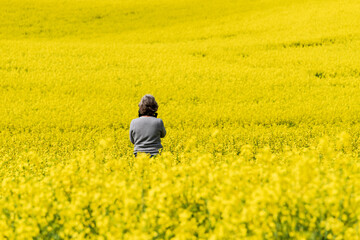 Fotografin in einem blühenden Rapsfeld bei der Arbeit