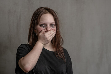 Frightened girl covers her mouth with her hands. Empty space for text