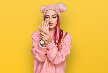 Young caucasian woman wearing casual clothes and wool cap suffering pain on hands and fingers,...