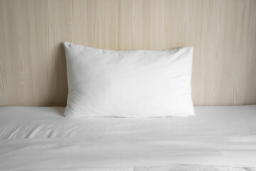 Fototapeta na wymiar empty and alone one pillow on white bed and wood headboard or brown wooden wall background in bedroom at home and feel lonely single or nobody for sleep relax at night or morning wake up comfortable