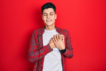 Young hispanic man wearing casual clothes smiling with hands on chest with closed eyes and grateful gesture on face. health concept.