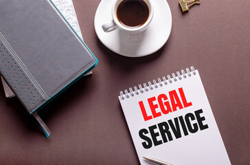 On a brown background, diaries, a white cup of coffee and a notebook with LEGAL SERVICE