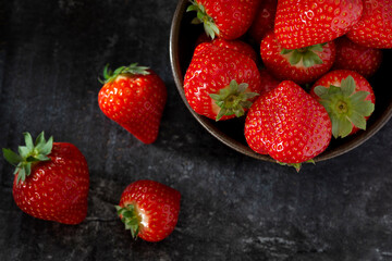 strawberries in a bowl on a dark gray background low key studio natural light 