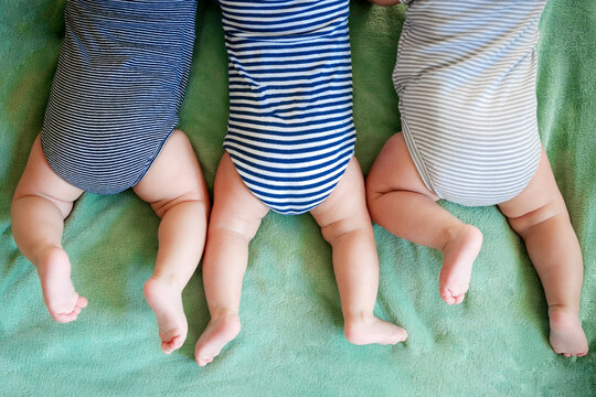 Newborn triplets boys lie on a stomach on a blanket