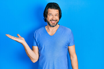 Fototapeta premium Middle age caucasian man wearing casual clothes smiling cheerful presenting and pointing with palm of hand looking at the camera.