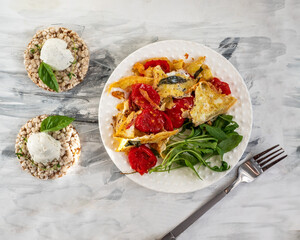 Omelet with spinach and tomatoes, fresh arugula on a white plate and slices with cream cheese
