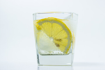 Lemon with ice in a glass. Refreshing drink with lemon. Cold cocktail