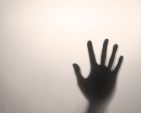 shadow human hand or people palm on window frosted glass or sepia door for near death or murder assassin to help and dark ghost horror concept in toilet room on warm white light background with space