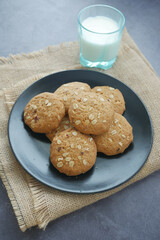 stack of oat cookies and milk on black background