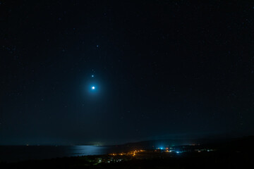 Amazing twilight starry sky, the moon reflecting in the sea, Venus and Jupiter composing the beautiful night scene view from above of the city of Uehara. Iriomote Island. © Renata Barbarino