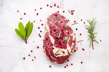 Raw Rib Eye Steak set up  on white concrete background. Flat Lay of fresh raw beef steak with...