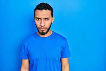 Obraz premium Hispanic man with beard wearing casual blue t shirt skeptic and nervous, frowning upset because of problem. negative person.