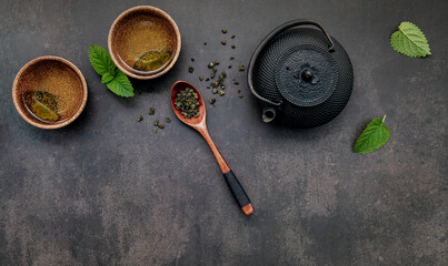  Black cast iron tea pot with herbal tea set up on dark stone background.