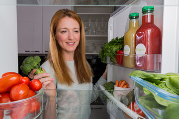 Open fridge from the inside, glass shelves with colourful vegetables, bottles of organic juices....