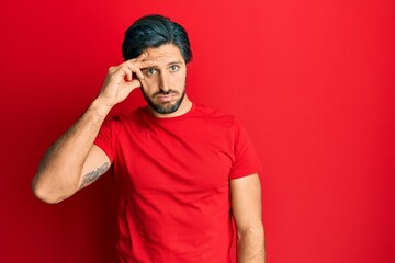 Young hispanic man wearing casual red t shirt worried and stressed about a problem with hand on forehead, nervous and anxious for crisis