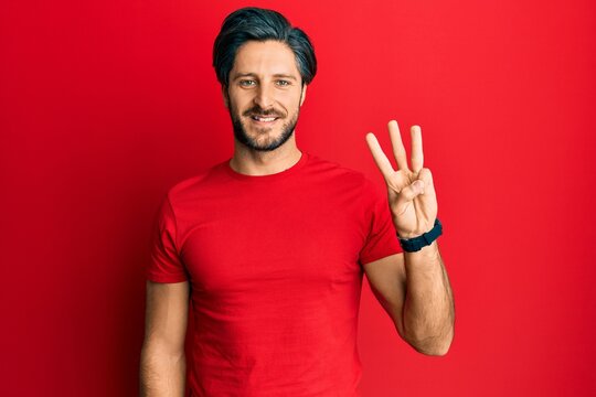 Young hispanic man wearing casual red t shirt showing and pointing up with fingers number three while smiling confident and happy.
