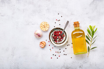 Glass bottle of olive oil and olive branch set up on white concrete background.