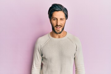 Fototapeta premium Young hispanic man wearing casual winter sweater winking looking at the camera with sexy expression, cheerful and happy face.