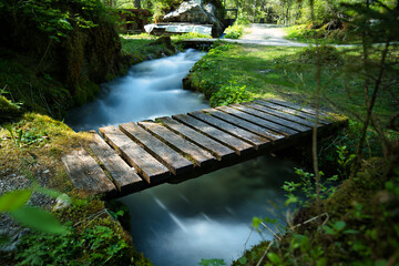A small floating river under a wooden bridge captured as a timelapse