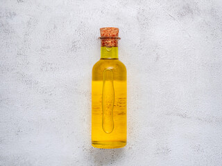 Glass bottle of olive oil and olive branch set up on white concrete background.