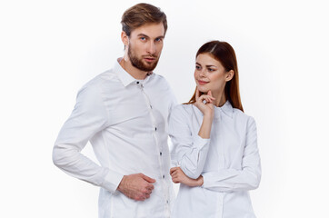 a man and a woman in identical shirts are gesticulating with their hands on a light background.