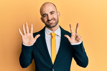 Young hispanic man wearing business suit and tie showing and pointing up with fingers number eight while smiling confident and happy.