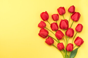 Bouquet red tulips on a yellow background, flat lay, copy space. Flower background