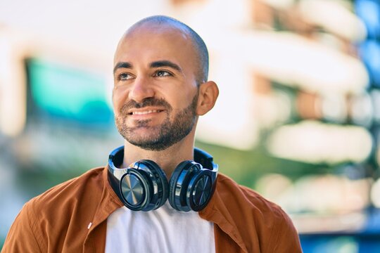 Young hispanic bald man smiling happy using headphones at the city