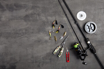 Fishing tackle - fishing spinning rod, hooks and lures on gray background. Active hobby recreation concept.