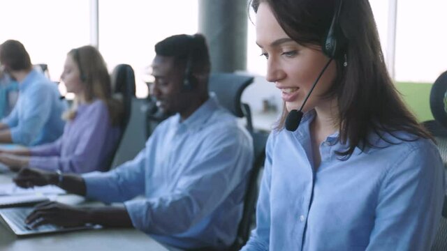 Call center worker accompanied by his team. Smiling customer support operator at work.