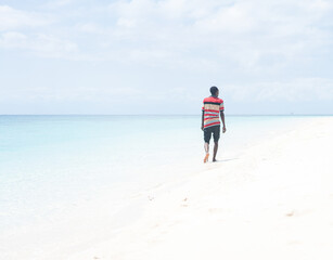 Black African young man walking on the beach