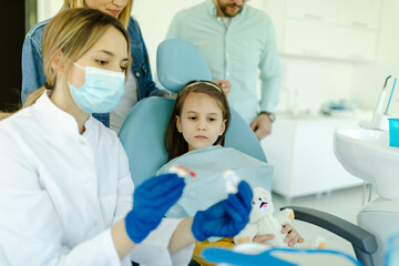 Obraz premium The doctor shows to girl and parents how the prosthesis is used and how it affects the teeth.