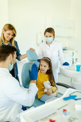 Man doctor is giving hi five to little girl after a successful dental examination.