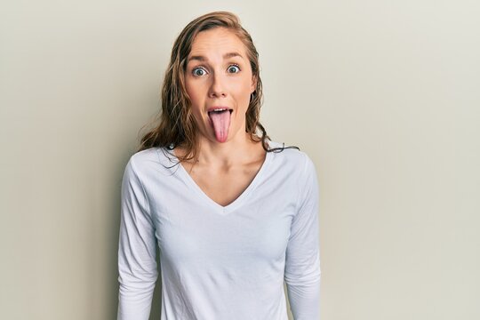 Young blonde woman wearing casual clothes sticking tongue out happy with funny expression. emotion concept.