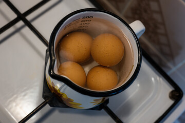 Four boiling eggs in a mug.