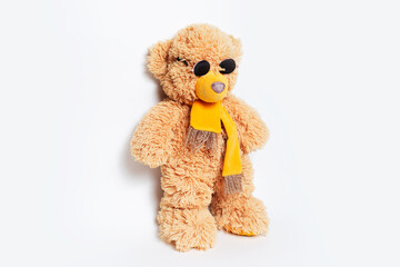 Toy of teddy bear wearing round sunglasses on white studio background.