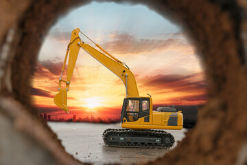 Crawler excavator are digging soil in the tunnel construction site. With a sunrise background  of...