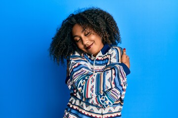 Beautiful african american woman with afro hair wearing casual clothes hugging oneself happy and positive, smiling confident. self love and self care