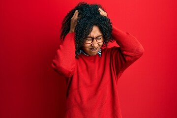 Fototapeta na wymiar Beautiful african american woman with afro hair wearing sweater and glasses suffering from headache desperate and stressed because pain and migraine. hands on head.