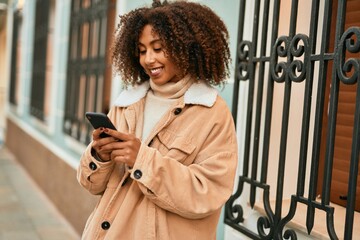 Young african american woman smiling happy using smartphone at the city.