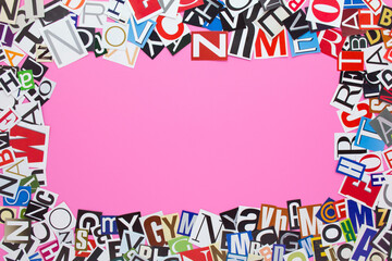 Alphabet letters cutting from paper magazine on pink background with copy space for text. Colorful abstract collage from clippings with newspaper magazine letters.