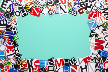 Alphabet letters cutting from paper magazine on azure green background with copy space for text....