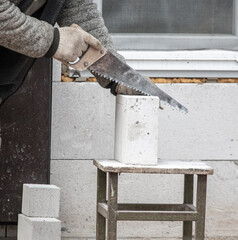 A worker cuts a brick with a saw.
