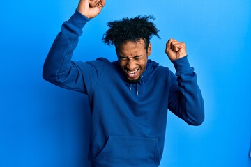 Naklejka premium Young african american man with beard wearing casual sweatshirt celebrating surprised and amazed for success with arms raised and eyes closed