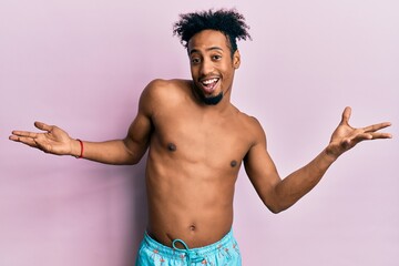 Fototapeta premium Young african american man with beard wearing swimsuit clueless and confused expression with arms and hands raised. doubt concept.