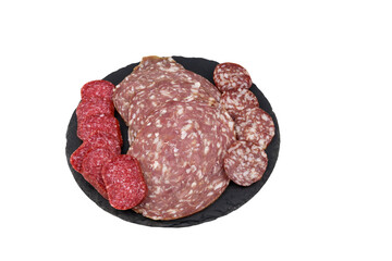 Different tasty sliced salami sausage on a black slate serving board isolated on white background