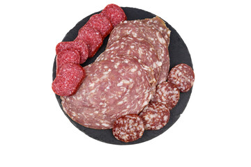 Different tasty sliced salami sausage on a black slate serving board isolated on white background